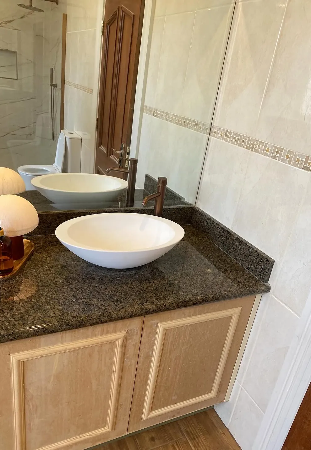 White vessel basin on a dark granite vanity with a copper tap