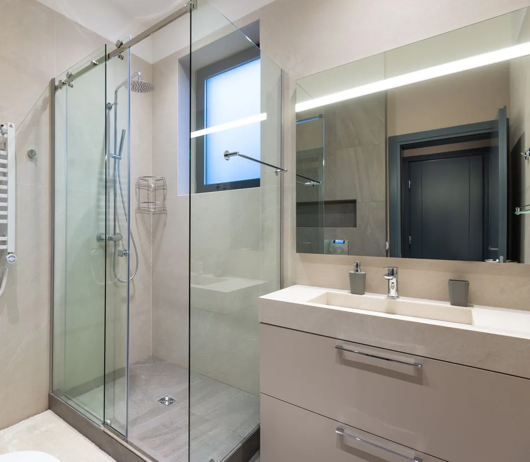 A modern bathroom with a glass shower, a heated towel rail and a lit mirror