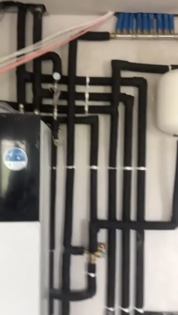 Heat pump pipework with black insulation and an underfloor heating manifold